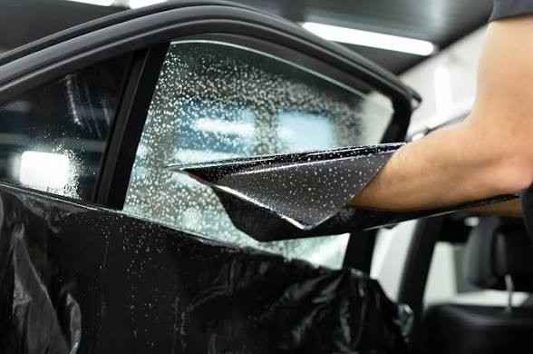 Squeegee smoothing freshly applied window tint